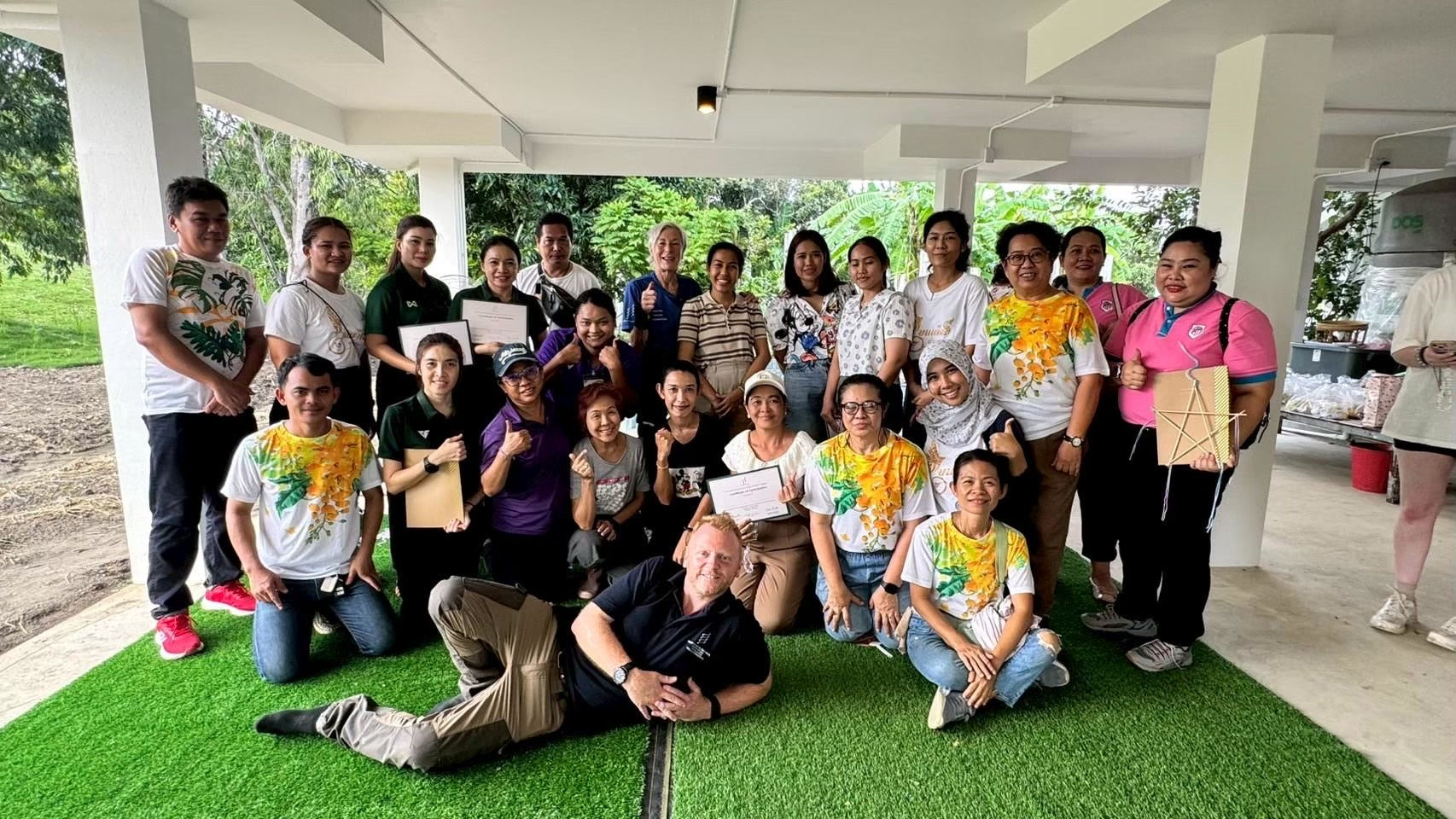 Group of people posing for a photo outdoors on a green artificial turf training group