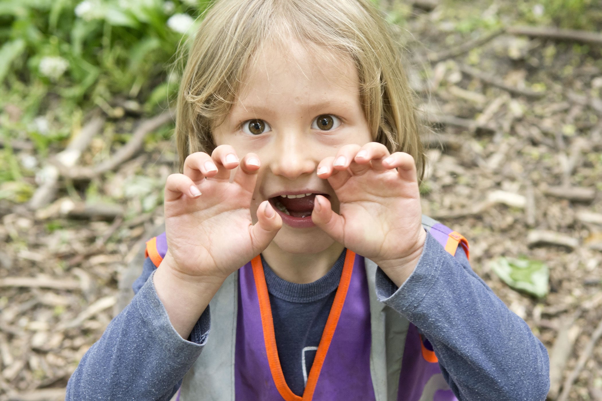 A child looking closely at something found on the woodland floor