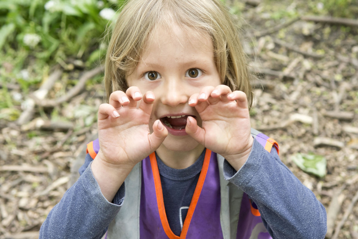 A child close to the camera, framing her own eyes with her hands