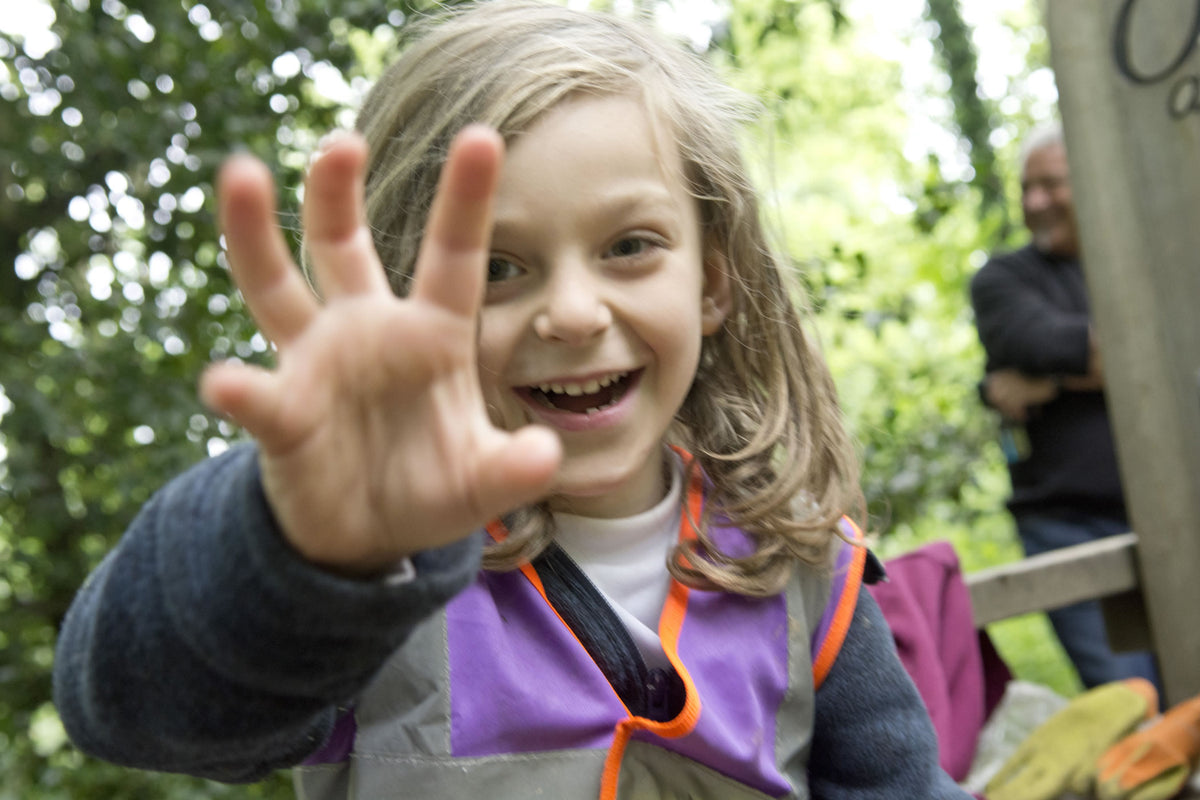 A child close to the camera, hand raised, delighted