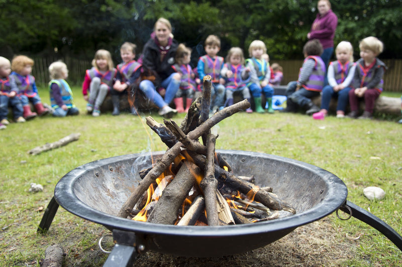 A fire burning in a fire bowl with a group seated in a circle beyond it