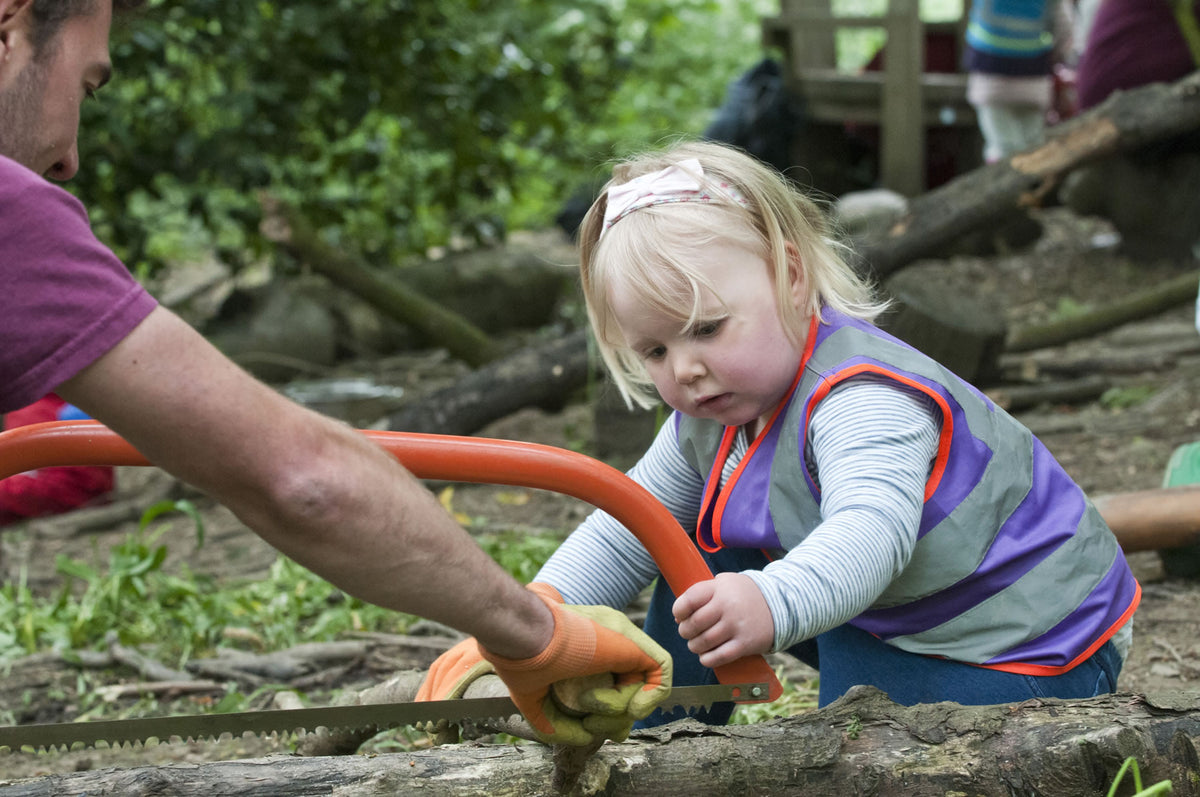 An adult steadying a bow saw for a child